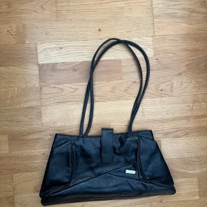 Svart väska  - En svart handväska med ett flertal fack i 