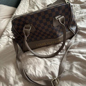 brun beige väska med axelband - Superfin väska med stort utrymme och handtag och axelband. Mycket plats och har hållit väldigt bra. 