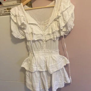 Fin vit klänning -  Säljer min super gulliga vita volangklänning då den inte kommer till användning längre, man kan knäppa knapparna och knyta banden fram om man vill den är även väldigt stretchig i midjan, kontakta mig vid frågor💞