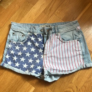 Jeansshorts med amerikanska flaggan  - Jeans shorts med amerikanska flaggan, ganska korta, använda kanske 4 ggr. Ganska tajta i storlek W30 ca S/M