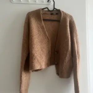 Kort beige/brun cardigan. Den är mjuk och sticks inte 