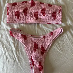 Rosa bandeau bikini med röda hjärtan på. Endast tvättad. Den är ifrån SHEIN. Finns inte kvar på hemsidan. Storlek M. 