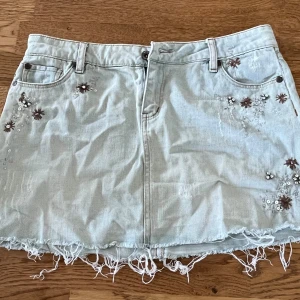 Jeanskjol - Jättefin jeanskjol med fina blomdetaljer och glitter som tyvärr inte kommer till användning💓 Det står storlek L men skulle säga att den passar S-M. Skriv om ni har några frågor!💕Pris går att diskuteras vid snabb affär💓