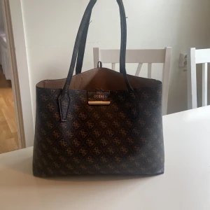 Brun GUESS handväska  - Bra skick förutom handtaget är lite slitet, får plats med mycket tex en dator 
