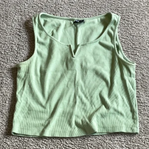 Mintgrönt linne - Fin v-detalj fram på bröstet Tyget är ribbat och lite tjockare 