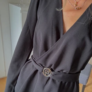 Blus med bälte - Chiara Forthi - Säljer denna svarta blus som har ett bälte i midjan. Bältet har en guldig detalj på sig. Bältet går att ta bort. Använd två gånger så skicket är bra.