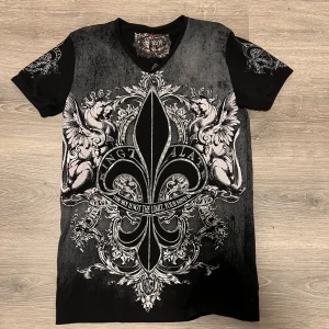 Affliction liknande tröja - Svart tshirt med massa bling bling på eller de kanske heter rhinestones. Affliction liknande är långsökt men vet inte vad det är för tröja😭