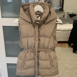 Väst - Skit skön beige väst jag köpte förra året då jag bara använde den under hösten men jag slutade använda den. Den är varm och har luva. Man kan spänna åt midjan och den har knappar vid fickorna😍 köptes för 500kr