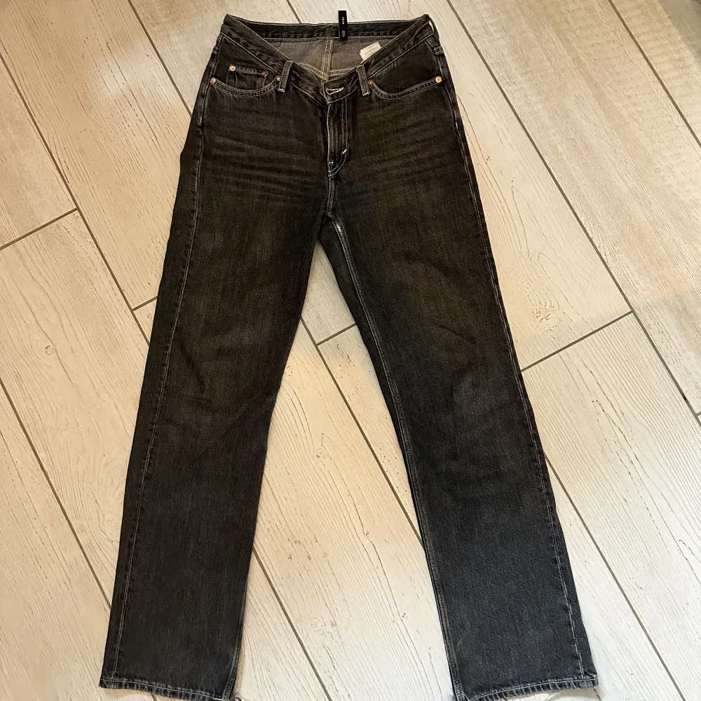 Mörkgråa lågmidjade raka jeans från Weekday med ljusa sömmar. Storlek 27. Slitna längst ner på benen på baksidan men det är inget man tänker på när man väl har på dem. . Jeans & Byxor.