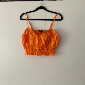 Orange sommartopp från Primark  - Orange sommartopp och magtröja i storlek 38 från Primark. Toppen är i bra skick då den endast används ett fåtal gånger. Toppen är lite liten i storleken. 