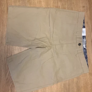 Beige shorts - Ny pris 299kr                                                                        Helt oanvända shorts                                                             Ett par beige shorts med knapp och dragkedja. De har en enkel design och ser bekväma ut för vardagsbruk. Blandning mellan linne och bomull