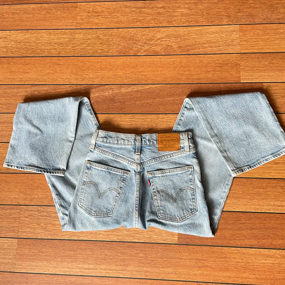 Ett par ljusblå jeansbyxor från Levi's med klassisk femficksdesign och en läderetikett på baksidan. Byxorna har en rak passform och är tillverkade i denim.. Farkut & Housut.