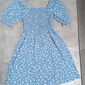 Klänning - En blå klänning med blommor som sällan använts ☺️🌸