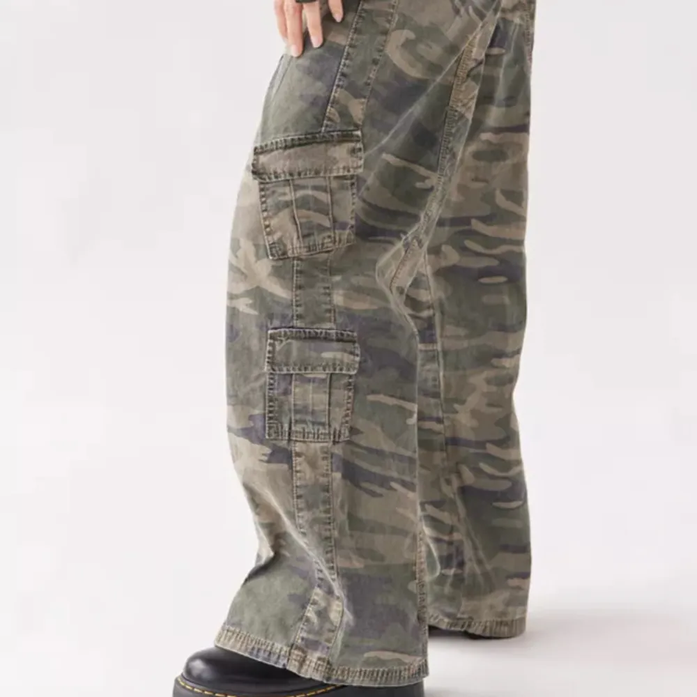 Pösiga Y2K camouflage cargo byxor från Urban outfitters. Stretchig midja och i bra kvalite. Endast använd någon gång då dem är långa på mig som är 157cm. Bra kvalite på materialet och inköpta för 800kr.. Farkut & Housut.