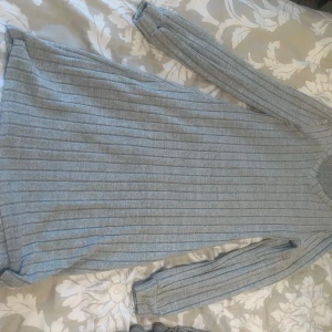 Grå ribbad klänning - En grå ribbad klänning med långa ärmar. Klänningen har en enkel och stilren design, perfekt för vardagsbruk.