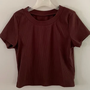 T-shirt  - Brun croppad t-shirt från New Yorker, strl s/36. Väldigt bra skick. Materialet är väldigt stretchigt. Säljer den då den inte kommer till användning längre. Kolla sista bilden för en mer rättvis bild av färgen 💕