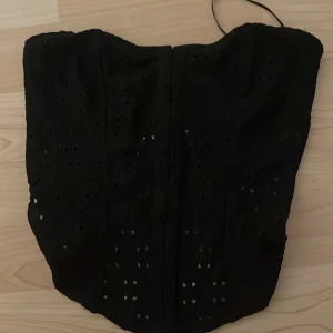 Svart lite spetsig korsett topp - Säljer då den är förliten, prislappen kvar och överstryken då jag fick den i present. Storlek xs och endast testat