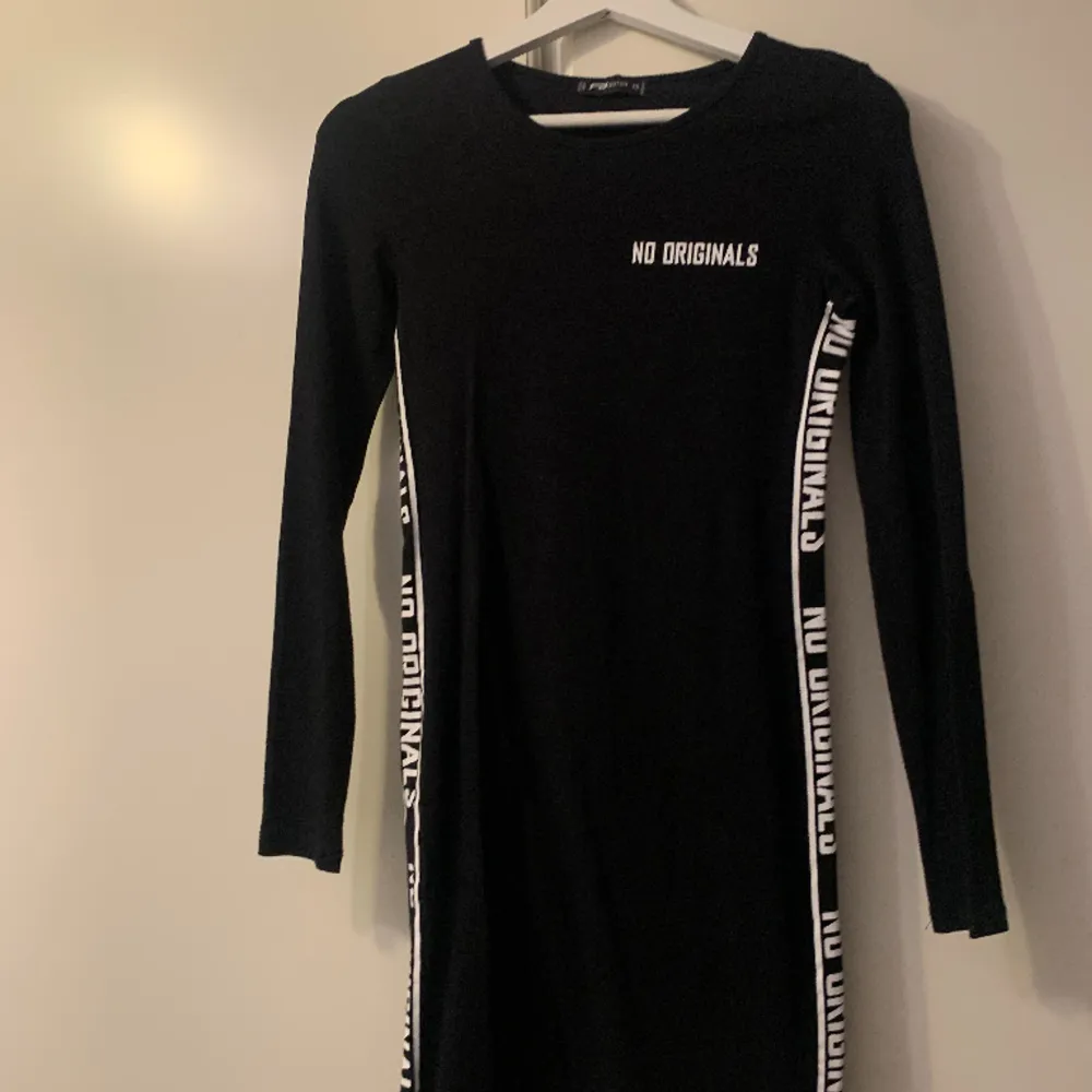 Svart klänning med text ”No originals” i vit vid båda sidorna av klänningen. Och vid vänster bröst. Sitter tight och snyggt på och visar kurvorna, använts ca 2/3 gånger.. Mekot.