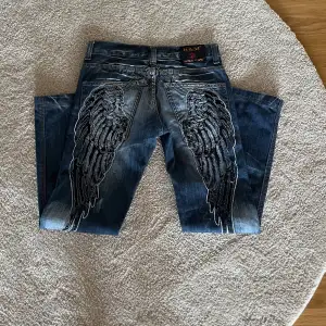 Super coola jeans med vingar på baksidan! Från komso lupo, super bra skick. midjemått: 38cm, innerbenslängd: 78cm, ytterbenslängd: 96cm