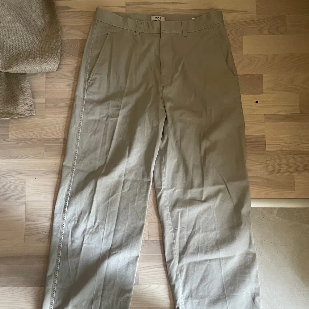 Ett par beiga Chinos från Cos, väldigt skön passform och faller snyggt över skorna! Jag har w33 och är 186cm, sitter väldigt bra Köpta för 1.200 men säljer för 350. Farkut & Housut.