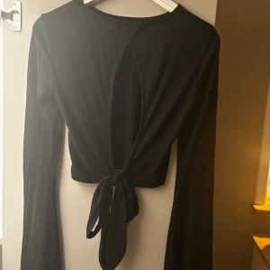 Topp med öppen rygg, NA-KD - Jättefin croppad topp från NA-KD, öppen rygg med knytbara band samt ribbat tyg och utsvängda armar. Använd fåtal gånger i nyskick, strl s (normal i storlek), säljer direkt för 250 men går att diskutera!