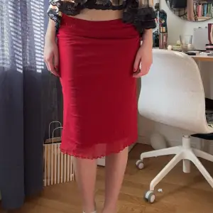 En röd tunn knälång kjol. Jättefin och strechig! Hör av er vid frågor!🫶