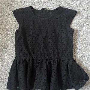 Svart spets topp med volang - jättefin kortärmad topp med blommigt mönster och en volang nedtill. väldigt fint skicka då jag aldrig använt eftersom jag inte gillar hur den sitter på mig eller vet hur jag ska styla. Passar bra till angiven storlek