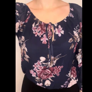 Blommig blus  - En mörkblå blus med blommor, köpt på Ullared. Mycket stretch i kragen och ett påsytt snöre för rosett där framme. Strl S men rymlig så passar fint på mindre och större storlekar.  Varsamt använd någon gång.  Köparen står för frakt. Diskuterbart pris