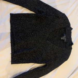 Svart glittrig tröja  - Svart glittrig tröja med öppen vid bröstet aldrig använd 