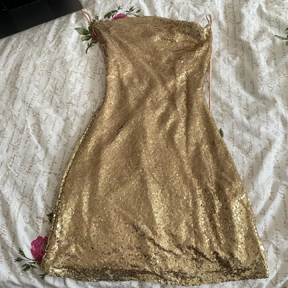Guld glittrig klänning från Nelly! Köpte runt december 2022 för att ha på nyår. använd 1 gång och säljer för jag inte har någon användning längre, jätte fint skick och inga tecken på användning alls. Skriv gärna innan köp! Kontakta för fler bilder . Klänningar.