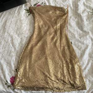 Guld glittrig klänning från Nelly! Köpte runt december 2022 för att ha på nyår. använd 1 gång och säljer för jag inte har någon användning längre, jätte fint skick och inga tecken på användning alls. Skriv gärna innan köp! Kontakta för fler bilder 