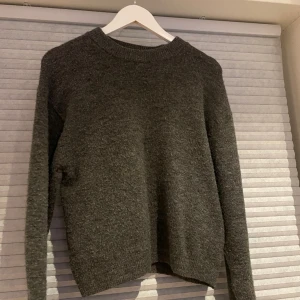 Stickad tröja - Sjukt fin stickad tröja i mörkgrå färg, enkel att styla och fin till verkligen allt. Säljer då den aldrig kommer till användning. Köpt hösten 2023. Ser nopprig ut på bilden men stämmer inte med verkligheten.
