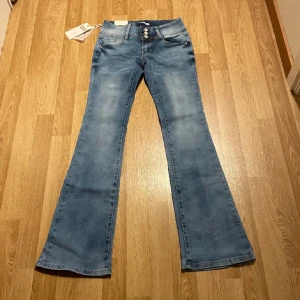 Lågmidjade bootcut jeans - Säljer dessa ljusblå lågmidjade bootcut jeansen. Jeansen är helt nya med lappar kvar och endast testade, av både mig och förra ägaren. Innerbenslängd: 80cm, midjemått: 34cm, men är stretchiga så passar även större mått. 