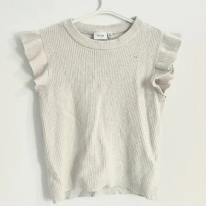 Söt vit stickad top - Söt vit stickad topp med volang! Köpt på Vila. Storlek xs. Har någon liten defekt som syns på bilden..🤍