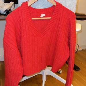Röd stickad tröja i en kortare ”boxigare” modell.