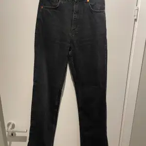 Högmidjade svarta jeans med en slits längst ner, från Bik Bok. Storlek 26/32
