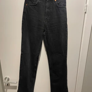 Svarta jeans - Högmidjade svarta jeans med en slits längst ner, från Bik Bok. Storlek 26/32