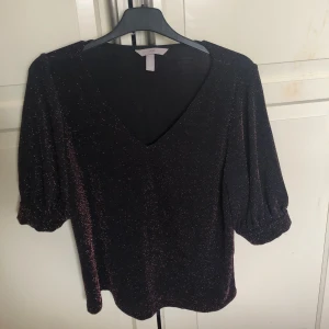 Fest tröja - Jätte fin glittrig fest blus med fin V ring, tunt fint material, helt ny aldrig använt, köpt från hm, svart med röd/orange glitter. Skriv gärna vid frågor eller funderingar❤️❤️