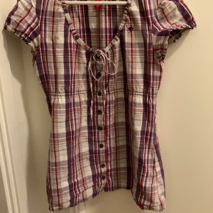 Lila rutig tröja - Super söt tröja med rutigt mönster. Den är i bra skick och går att knyta så den passar ens midja