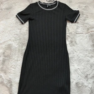 Svart t-shirt klänning - Svart t-shirt klänning från H&M, köpt för flera år sedan, använd fåtal gånger & därav säljer jag den. Sitter super bra, formar sig bra runt midjan, skön & snygg. Normal i storlek, inga defekter eller andra fel på den.