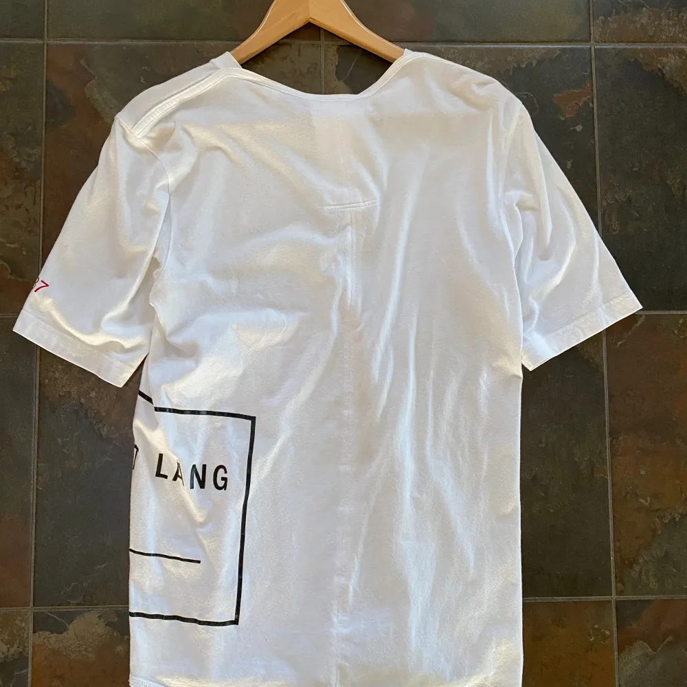 Storlek Small Helmut Lang ”PR Team” T-shirt som är i väldigt bra skick förutom 2 st små hål som är 1-2 mm stora (se bilder) men de syns knappt. Kostar över 1000 ny.. T-shirts.