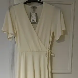 En vit omlotskläning från H&M som har kvar prislappen, säljs för den aldrig används. Den har en fläck längst ner på kjolen som fanns där när den köptes och vet tyvär ej vad det är. Original pris 250kr. Köparen står för frakten. 