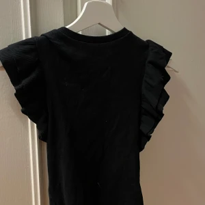 Ribbad volang tröja  - Fin svart tröja me volanger på armarna aldrig använd 