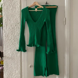 Grönt set, byxor och tröja, H&M - Supersnyggt set från H&M. Ribbstickat, tröjan har trumpetärmar och v-ringning. Byxorna är utsvängda med liten slits nedtill.  Lika skönt som ett mjukisset att bära. Sparsamt använt.