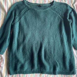 Grön stickad tröja från H&M - En bekväm grön stickad tröja från H&M med rund halsringning och långa ärmar. Tröjan har ett enkelt och stilrent mönster med ribbstickade muddar vid ärmslut och nederkant.
