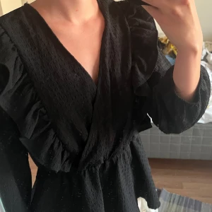 Svart blus - Fin svart blus med volanger 