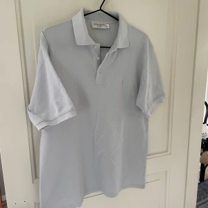 YSL Piké  - YvesSaintLaurent Piké i storlek M, passar även L. Den är i jättefint skick, i färgen ljusblå.