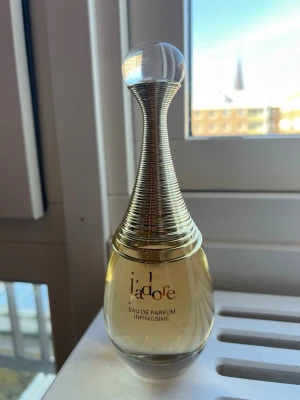 Dior J'adore Infinissime Eau de Parfum 100 ml - J'adore Eau de Parfum Infinissime från Dior i en elegant, droppformad flaska med guldfärgade detaljer och genomskinlig glaskropp. Parfymen har en lyxig och feminin design med en rund, klar kork och guldspiral runt halsen. Helt ny aldrig använd. Kommer utgå från sortimentet så köp den snabbt innan den försvinner. Självklart äkta 