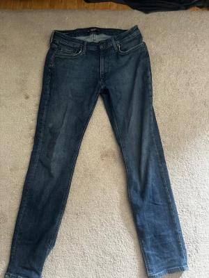 Mörkblå slim fit jeans - Säljer nu dessa snygga jeans från Jack and Jones i passform regular/clark, i storlek 28/32. Perfekta jeans nu inför sommaren. Bara höra av er i dm vid ev frågor eller funderingar.