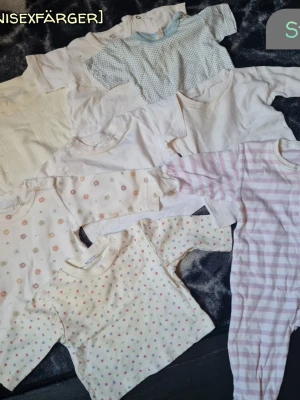 Baskläder i neutrala färger till bebis  - Säljer ett set med flera basplagg i mjuka pastellfärger och olika mönster som ränder, prickar och små blommor. Plaggen har långa + korta ärmar och är tillverkade i bomull. Färgerna går i vitt, ljusblått, beige och lila. Perfekt för den nyfödde. Storlek 56-62.